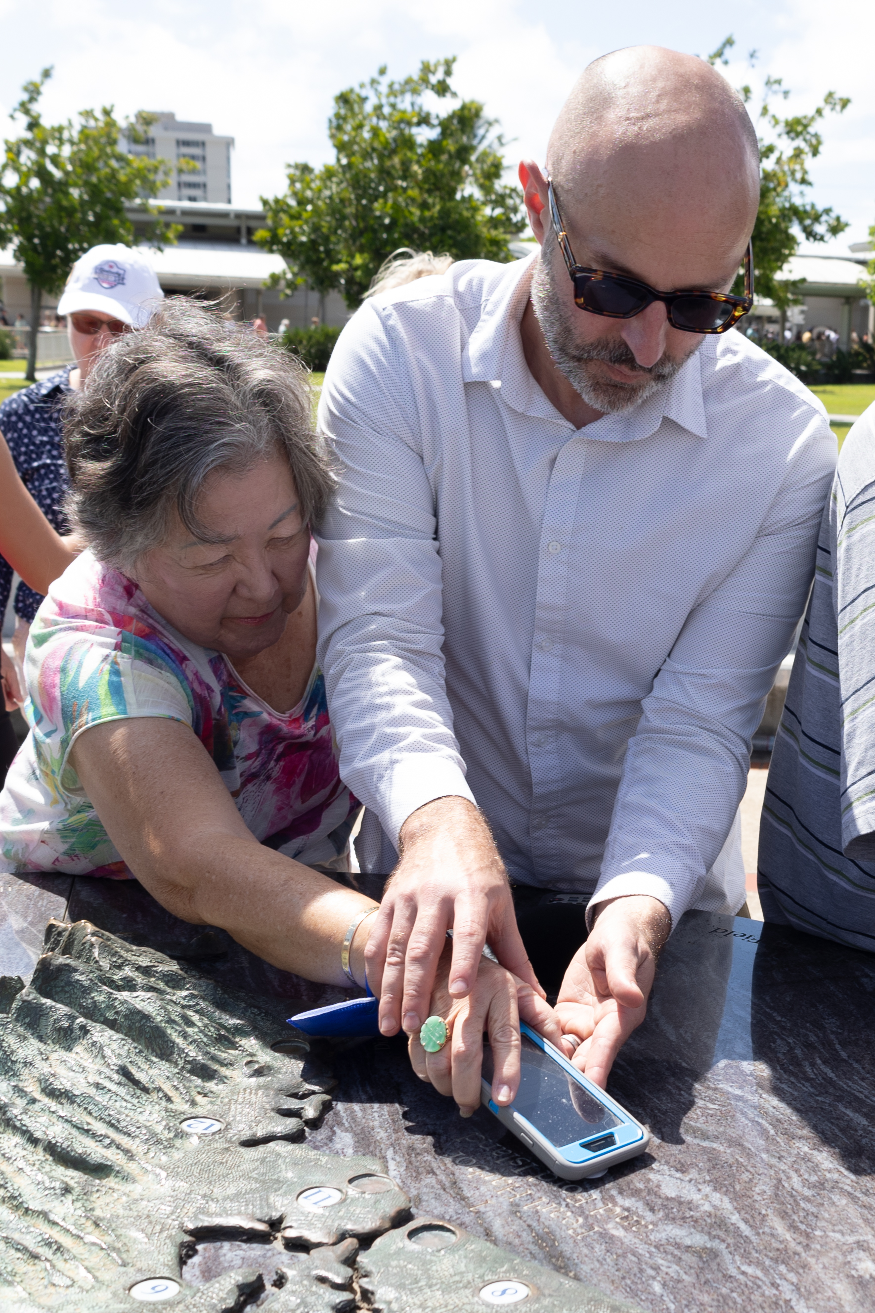 Photo of Testing Audio Description: Dr. Jordan Frith and a Hawaiian Association of the Blind research participant work with a NFC tag placed on an outdoor map at Pearl Harbor National Memorial (2023)